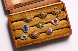 Antique gold gem-set rings with sapphires, rubies, emeralds and diamonds in an antique velvet ring box
