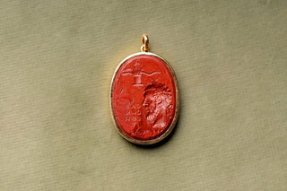 Glass intaglio pendant held in the hand for scale