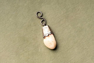 Red deer tooth pendant with S-scroll silver bail, angled view